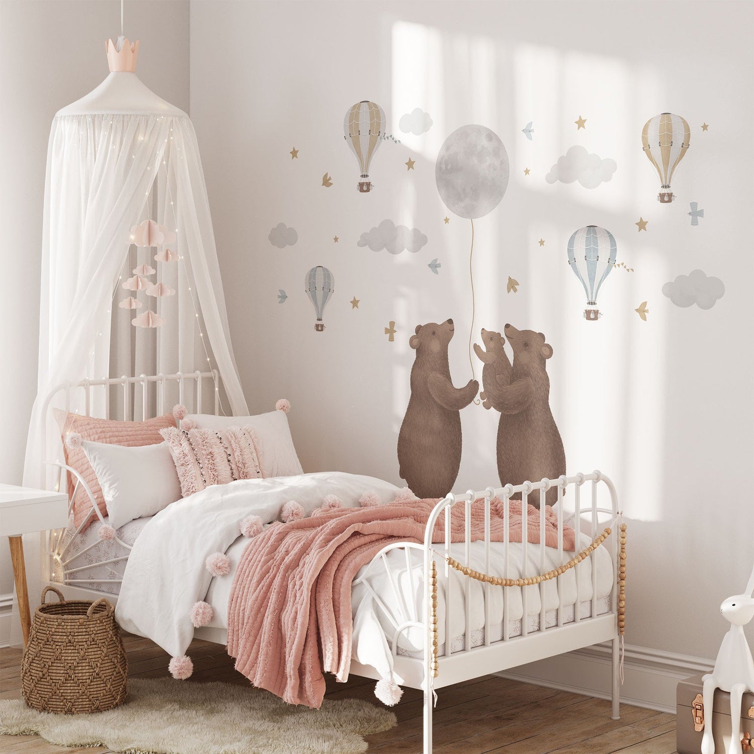 A cozy childrens bedroom features a canopy bed with pink and white bedding, whimsical Bears & Moon Stickers from My Store on the wall, and charm added by a wicker basket and small table.