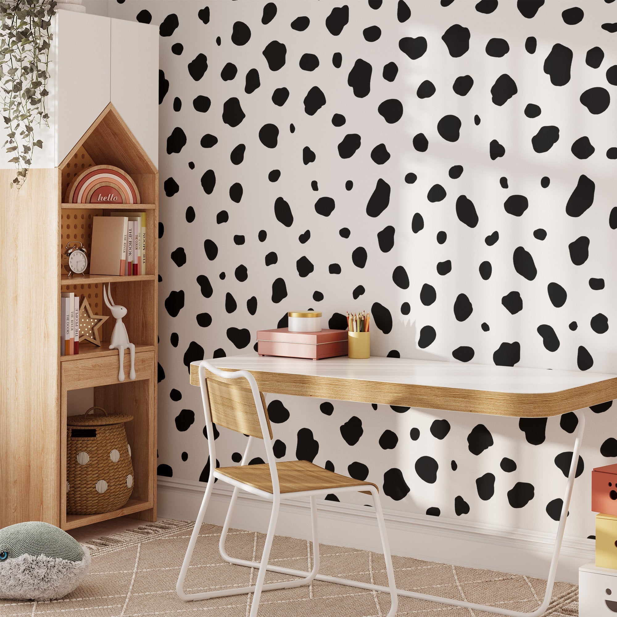 A minimalist study area includes a wooden desk, chair, and My Stores Dalmatian Spot Large Stickers on the wall. House-shaped shelving holds books and decor, while a plush toy lies on a striped rug. Hanging greenery adds nature above the self-adhesive backdrop.