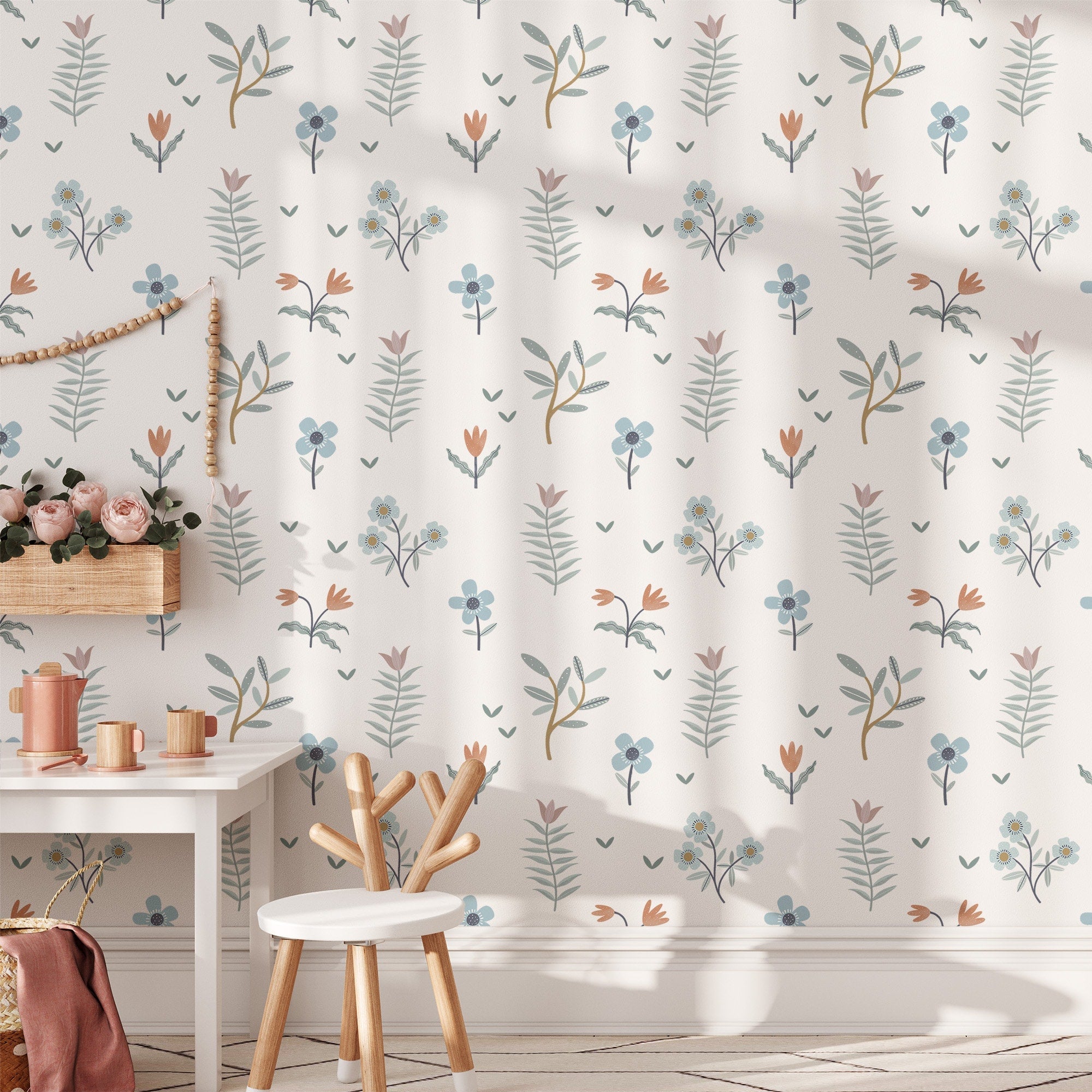 A minimalist childrens room features a white table and a round chair. The wall is decorated with My Stores Summer Mood Wall Stickers, showing floral patterns in orange, blue, and green. A rope hangs in the corner while sunlight gently illuminates the light wood floor.
